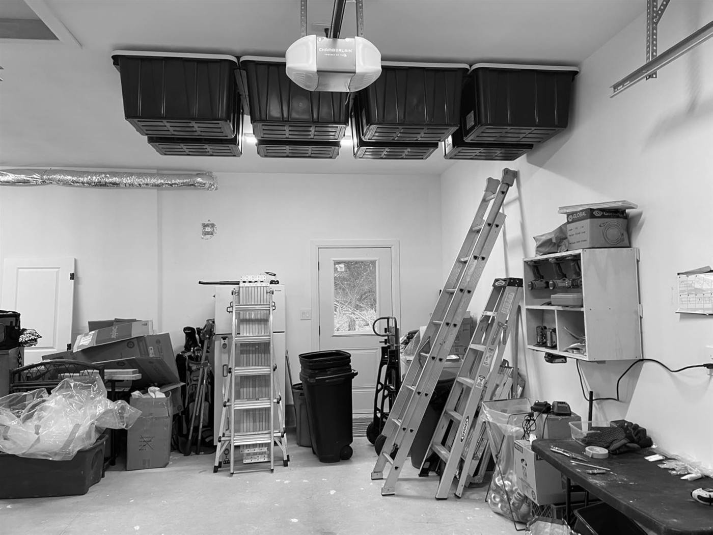 Black totes stored overhead while ladders and boxes wait below