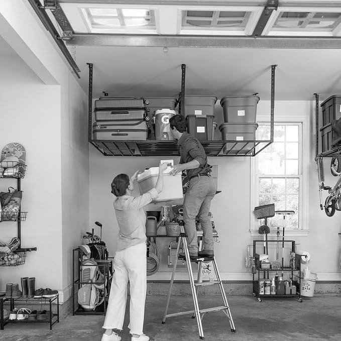 Two people lifting a tote onto an overhead garage rack