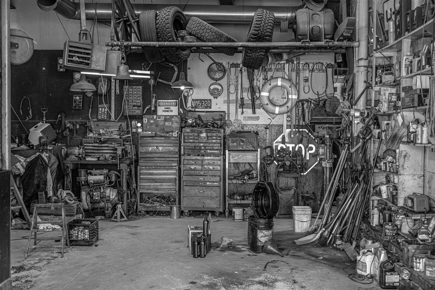A crowded workshop garage packed floor to ceiling with tools, tires and toolboxes